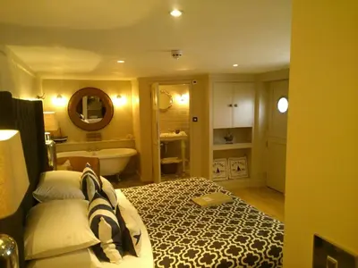 a bedroom with a bed and a bathroom with a tub at Headland House Luxury B&B in St Ives