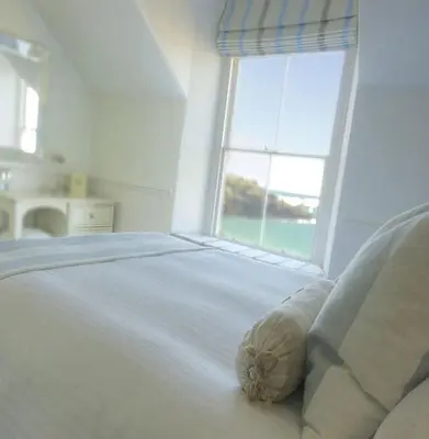 a white bed with a pillow in front of a window at Headland House Luxury B&B in St Ives