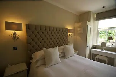 a bedroom with a large white bed with a large headboard at Headland House Luxury B&B in St Ives