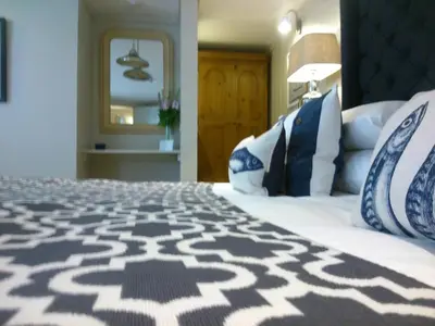 a bedroom with a large bed with blue and white pillows at Headland House Luxury B&B in St Ives