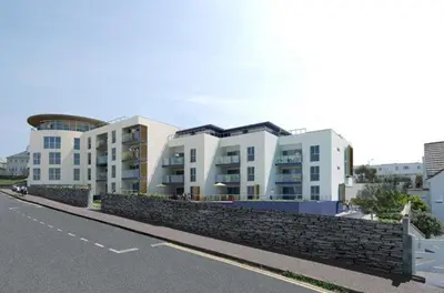 a building with a stone wall next to a street at 6 Ocean Gate apartment in Newquay