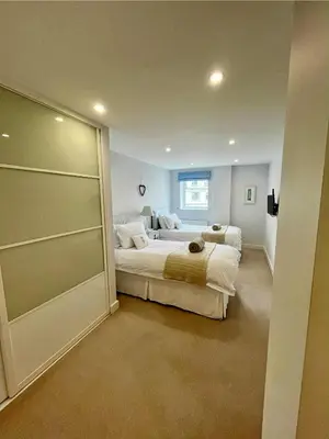 a bedroom with two beds and a sliding glass door at 6 Ocean Gate apartment in Newquay