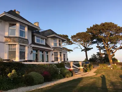 a large white house with a tree in the background at Porth Avallen Hotel in St Austell