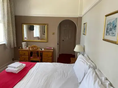 a bedroom with a bed and a dresser and a mirror at Porth Avallen Hotel in St Austell