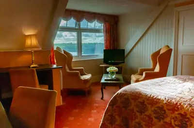 a hotel room with a bed and chairs and a window at Porth Avallen Hotel in St Austell