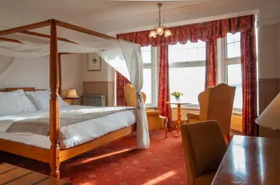 a bedroom with a canopy bed and a table at Porth Avallen Hotel in St Austell