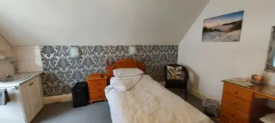 a bedroom with a bed and a dresser and a sink at Invernook in Newquay