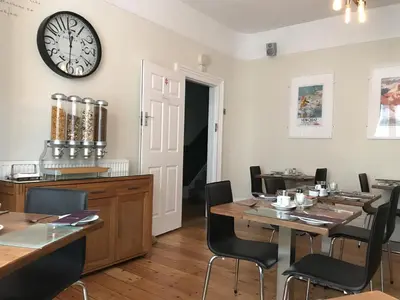 a dining room with tables and a clock on the wall at St Bernards in Newquay