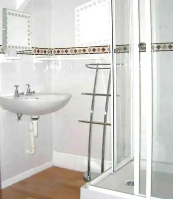 a white bathroom with a sink and a shower at Harrington Guest House in Newquay