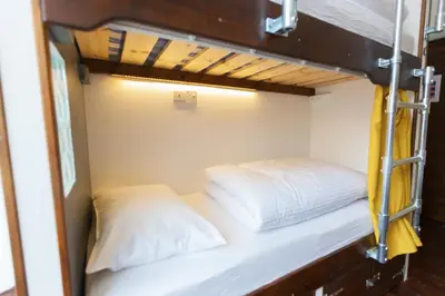 a bunk bed with two white pillows in a room at Cohort Hostel in St Ives