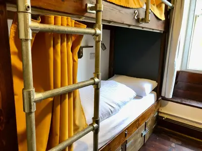a bunk bed in a train room with yellow curtains at Cohort Hostel in St Ives