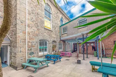 a patio with picnic tables in front of a brick building at Cohort Hostel in St Ives