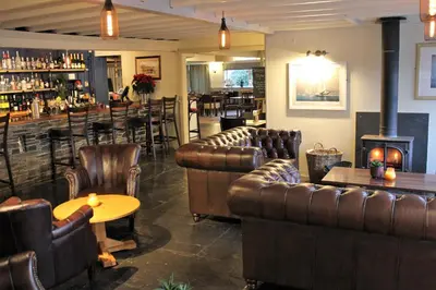 a bar with leather couches and a table and a bar at The Pityme Inn in Wadebridge
