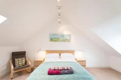 a bedroom with a bed and a chair at Camana in St Ives