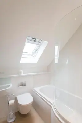 a white bathroom with a toilet and a skylight at Camana in St Ives