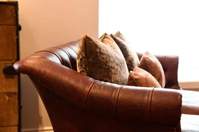 a brown leather couch with pillows on it at Padstow Townhouse in Padstow