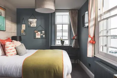 a bedroom with a bed and a desk and windows at Chainlocker in Falmouth
