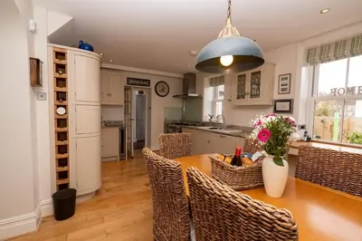 a kitchen with a wooden table with chairs and a dining room at Brookdale House in Wadebridge