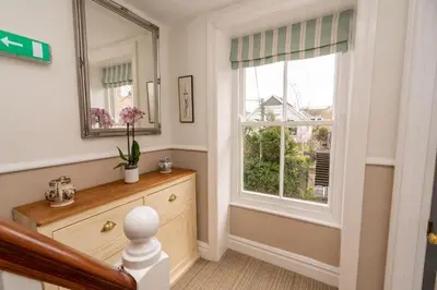 a hallway with a window and a dresser and a mirror at Brookdale House in Wadebridge