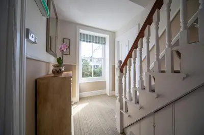 a hallway with stairs and a vase of flowers on a table at Brookdale House in Wadebridge