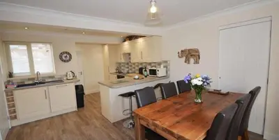 a kitchen with a wooden table with a vase of flowers on it at 2 Fernleigh Villas in Perranporth