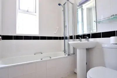 a white bathroom with a sink and a bath tub at Pentire Newquay Cornwall Hotel in Newquay