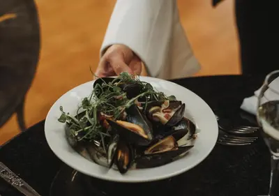 a person holding a plate of mussels on a table at Atlantic Hotel Newquay in Newquay