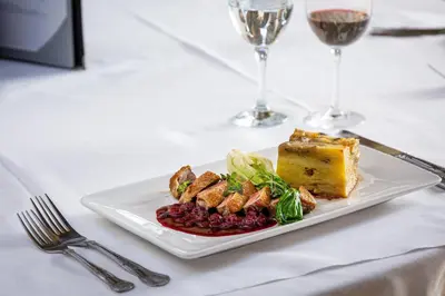 a plate of food on a table with glasses of wine at Atlantic Hotel Newquay in Newquay