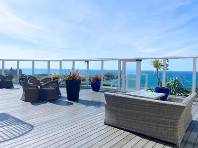 a deck with chairs and the ocean in the background at Atlantic Hotel Newquay in Newquay