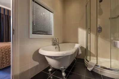 a bathroom with a tub and a glass shower at Atlantic Hotel Newquay in Newquay