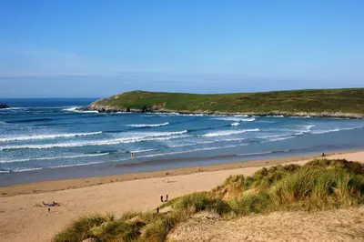 a beach with people on the sand and the ocean at Nanis in Crantock