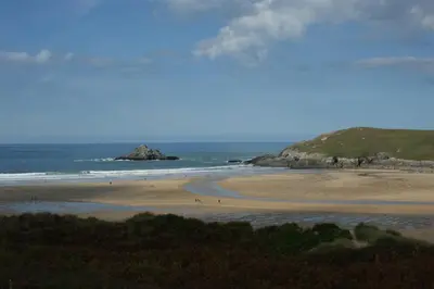 a beach with a group of people walking on the sand at Nanis in Crantock