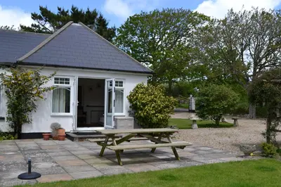 a picnic table in front of a white house at Nanis in Crantock