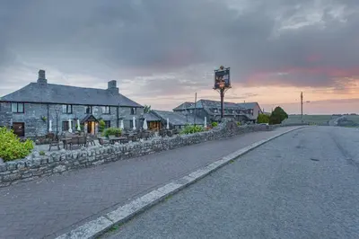a cobblestone street in front of a stone building at The Jamaica Inn, Bodmin, Cornwall - The Coaching Inn Group in Bolventor