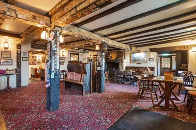 a living room with tables and chairs and a fireplace at The Jamaica Inn, Bodmin, Cornwall - The Coaching Inn Group in Bolventor
