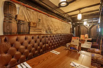 a brown leather bench in a room with a table at The Jamaica Inn, Bodmin, Cornwall - The Coaching Inn Group in Bolventor