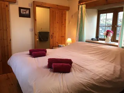 a large white bed with two red pillows on it at The Stable in Saint Clether