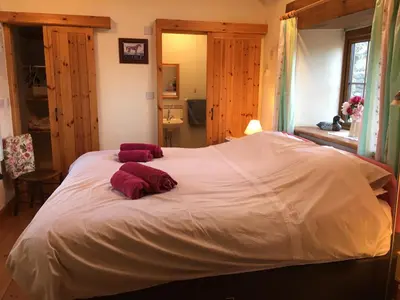 a large white bed with two red pillows on it at The Stable in Saint Clether