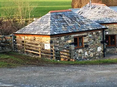 an old stone house with a fence in front of it at The Stable in Saint Clether