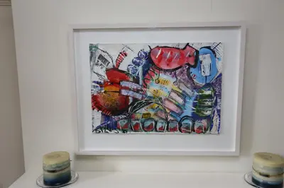 a painting in a white frame on a wall with two candles at Bedlam House in Newquay