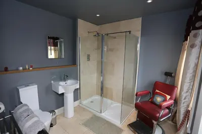 a bathroom with a shower and a red chair at Bedlam House in Newquay