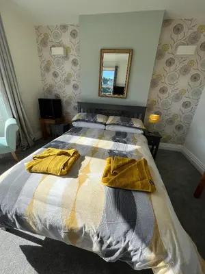 a bedroom with a bed with yellow towels on it at Penwyn Bed and Breakfast in Looe