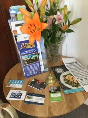 a table with a vase of flowers and books on it at Penwyn Bed and Breakfast in Looe