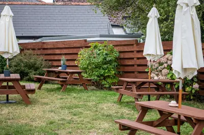 two picnic tables and two umbrellas in a yard at Three Tuns in Helston