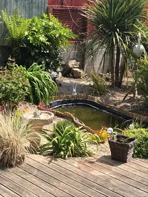 a small pond in a garden with a wooden deck at Gwynarth Guest House in Wadebridge