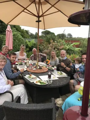 a group of people sitting around a table with an umbrella at Gwynarth Guest House in Wadebridge