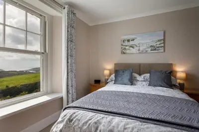 a bedroom with a bed and a window at Bucklawren Farm in Looe