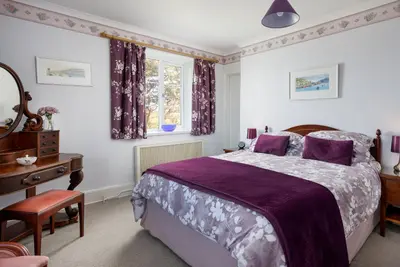 a bedroom with a bed and a desk and a window at Bucklawren Farm in Looe