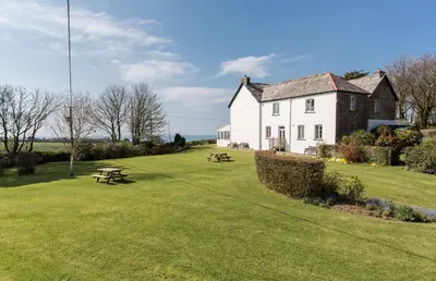 a large white house with a picnic table in front of it at Bucklawren Farm in Looe