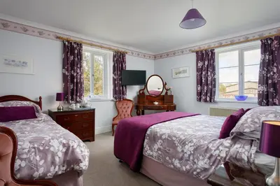 a bedroom with two beds and a mirror at Bucklawren Farm in Looe